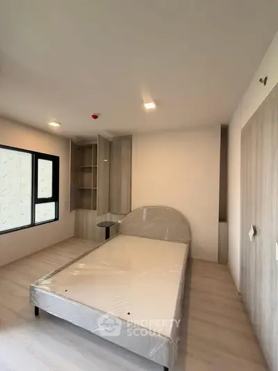 Modern bedroom with minimalist design and large window for natural light.