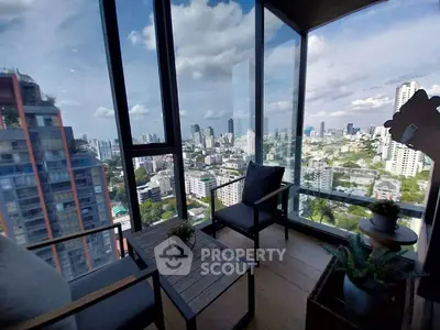 Stunning city view from a modern high-rise balcony with cozy seating area.