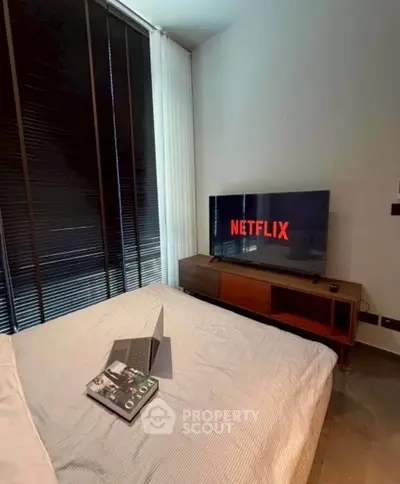 Cozy bedroom with modern decor, featuring a TV and laptop for entertainment.