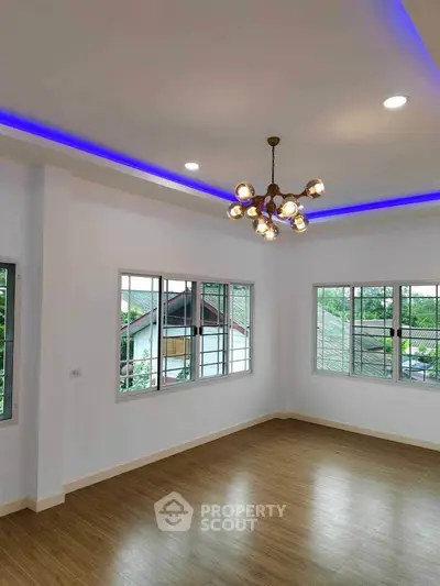 Spacious living room with modern lighting and large windows offering a scenic view.