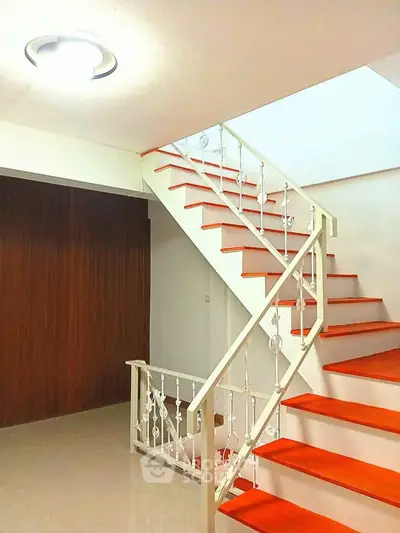 Modern staircase with red steps and white railing in a stylish home interior
