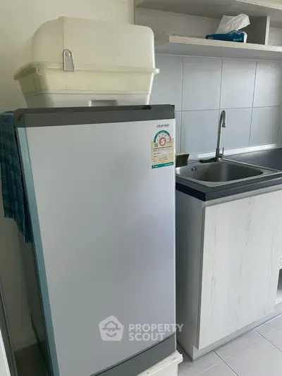 Compact kitchen with modern fridge and sleek sink area, perfect for urban living.