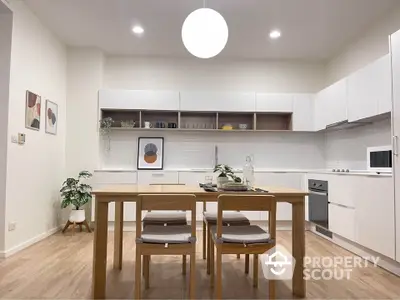 Modern kitchen with sleek white cabinets and wooden dining table in stylish apartment