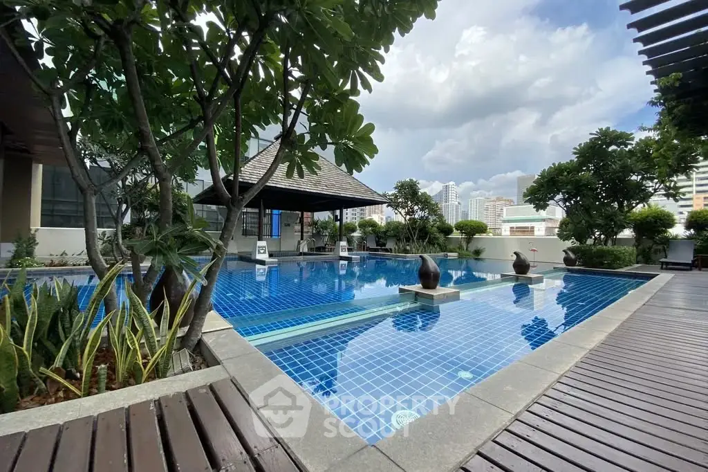 Luxurious outdoor pool area with lush greenery and city views, perfect for relaxation and leisure.