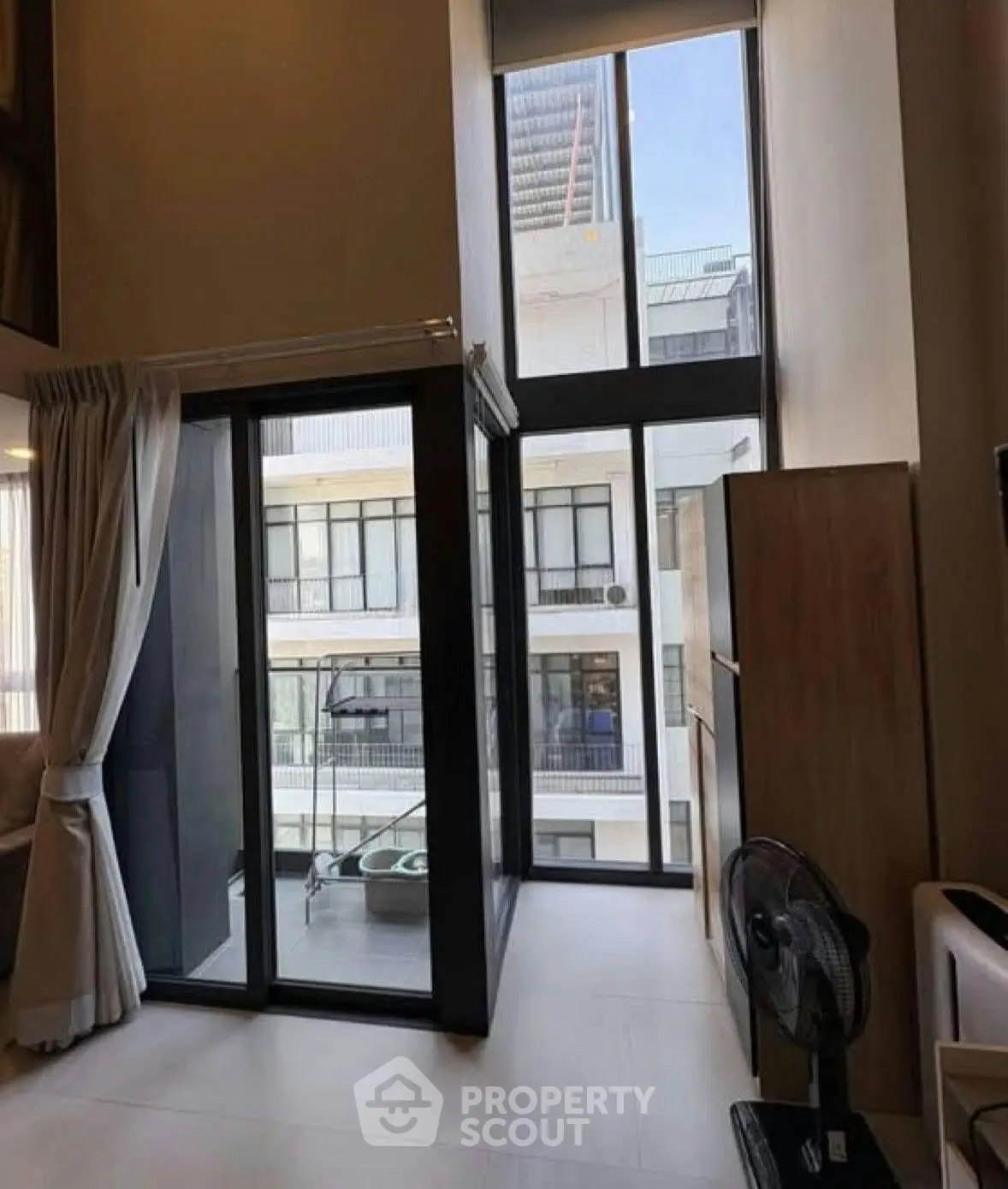 Modern apartment with floor-to-ceiling windows and balcony access, offering ample natural light and urban views.
