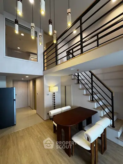 Modern duplex apartment with stylish lighting and open staircase, featuring a cozy dining area and sleek interior design.