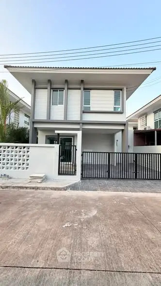 Modern two-story house with sleek design and gated entrance in a suburban neighborhood.