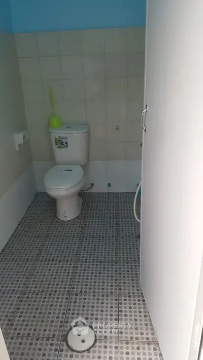 Simple bathroom with tiled floor and toilet in a real estate property.