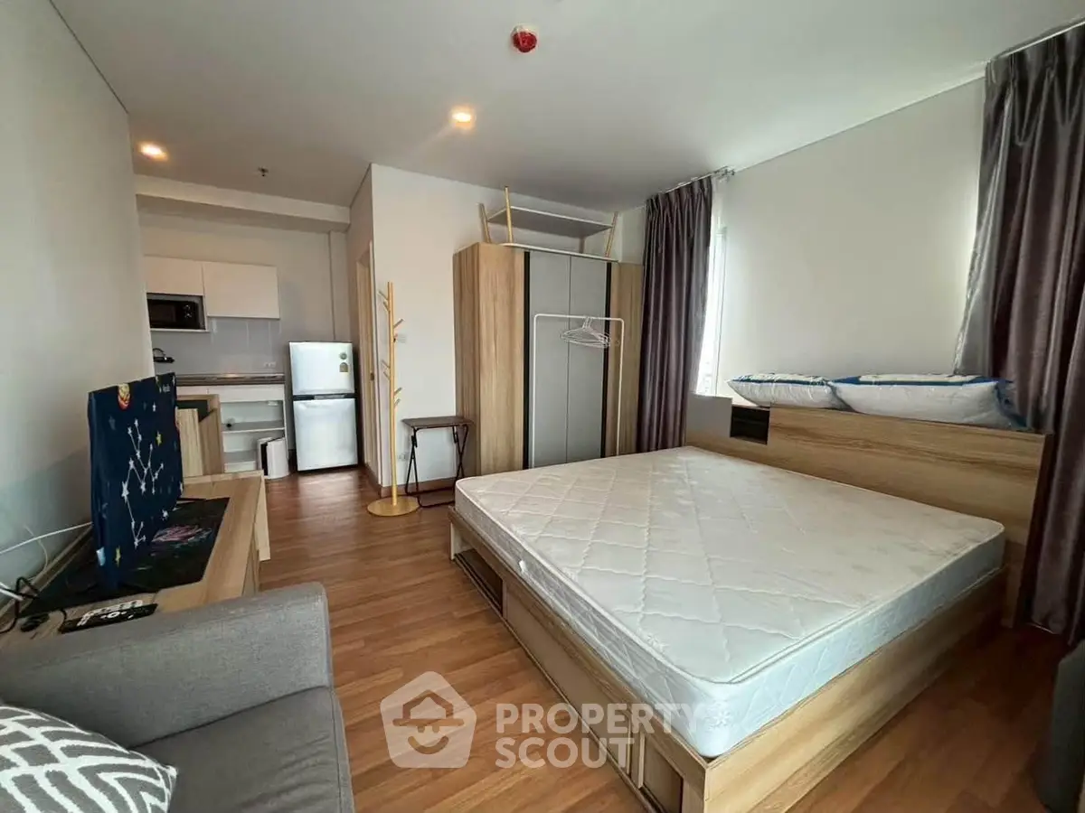 Modern studio apartment with open layout, featuring a cozy bed, compact kitchen, and stylish decor.