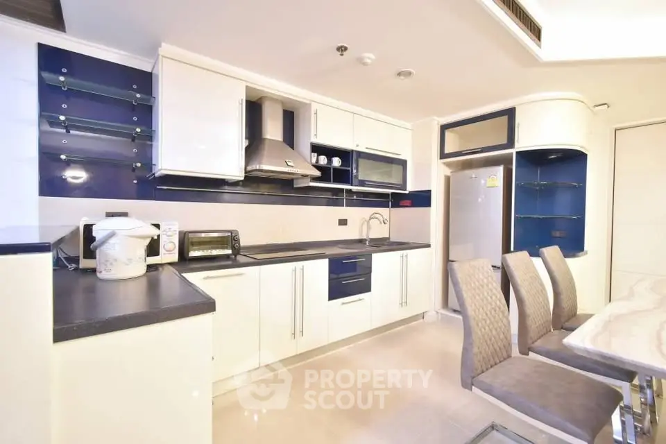 Modern kitchen with sleek cabinetry and dining area in contemporary apartment