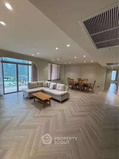 Spacious modern living room with elegant dining area and large windows offering city views.