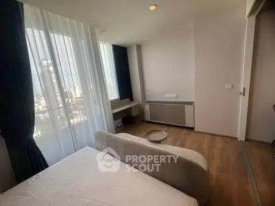 Bright bedroom with large windows and city view, featuring modern furnishings and wooden flooring.