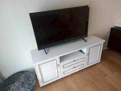 Modern living room with sleek TV stand and flat-screen TV on wooden floor.