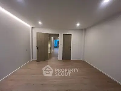 Spacious modern room with wooden flooring and recessed lighting, ideal for versatile living arrangements.