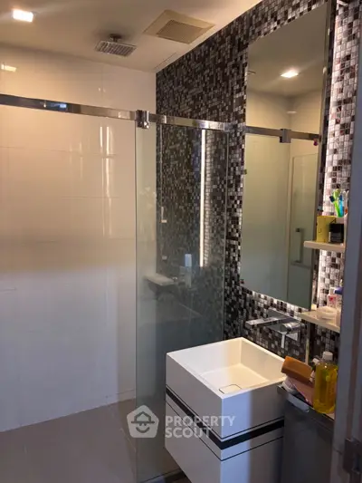 Modern bathroom with sleek design, glass shower, and stylish mosaic tiles.