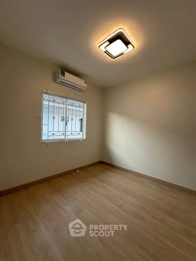 Spacious empty room with wooden flooring and modern ceiling light, perfect for customization.
