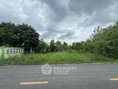 Vacant land plot with lush greenery and clear sky, ideal for development.