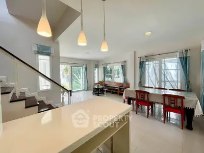 Spacious open-plan living and dining area with modern lighting and large windows.