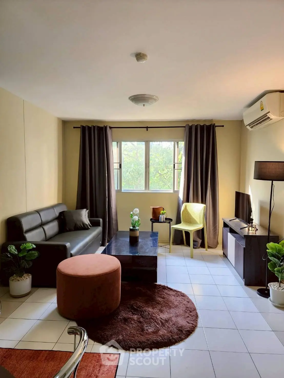 Cozy living room with modern decor, featuring a leather sofa, stylish coffee table, and large window with natural light.