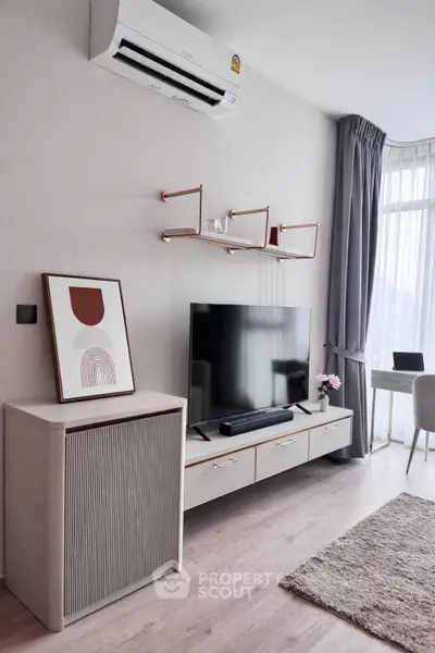 Modern living room with sleek furniture, wall-mounted TV, and large window for natural light.