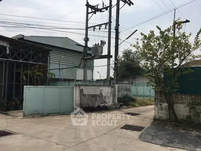 Industrial exterior with power lines and gated entrance in urban setting.
