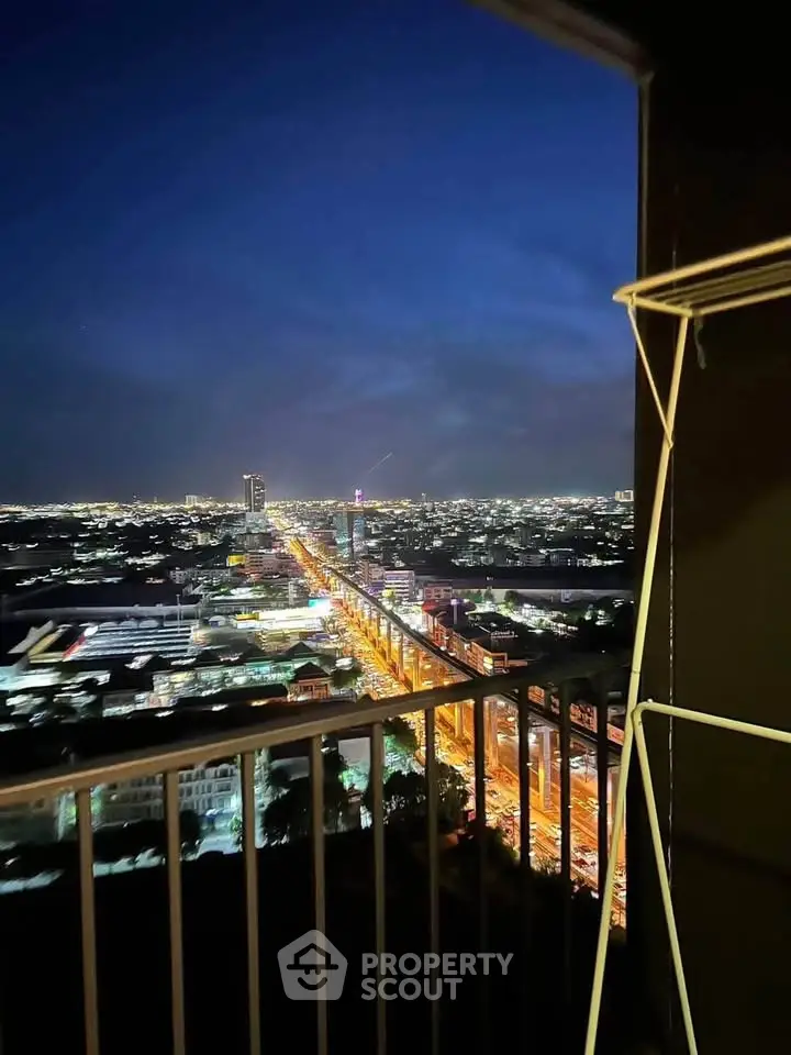 Stunning cityscape view from a high-rise balcony at night, showcasing vibrant city lights.