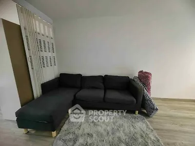 Cozy living room with modern dark sofa and plush rug on wooden floor