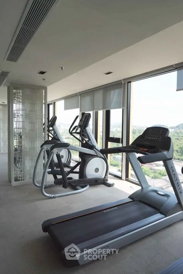 Modern gym with treadmills and exercise equipment in a high-rise building with scenic views.