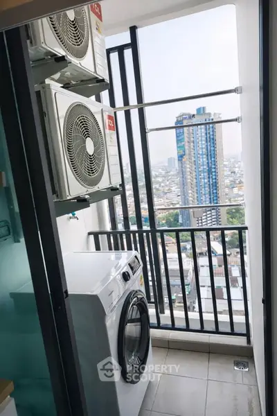 Compact balcony with city view, featuring washing machine and air conditioning units.