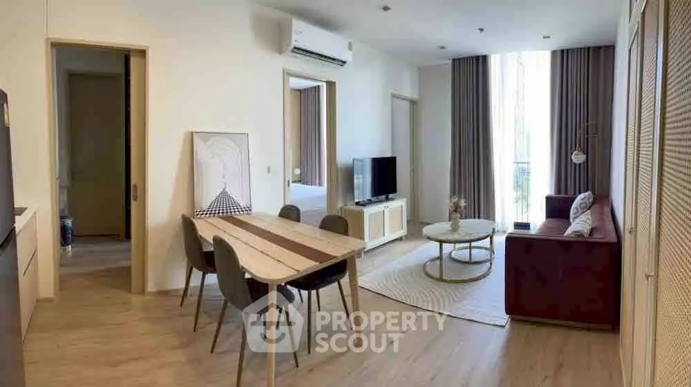 Modern living room with dining area, stylish furniture, and natural light from large windows.