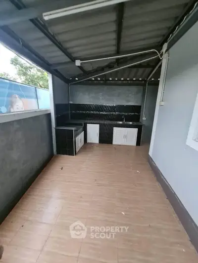 Spacious outdoor kitchen area with tiled flooring and modern cabinetry.