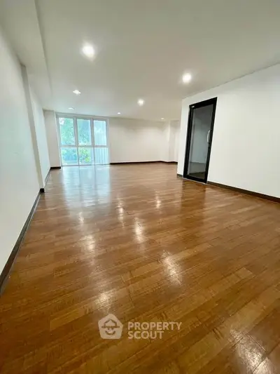 Spacious empty living room with wooden flooring and large windows