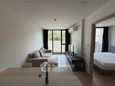 Modern living room with balcony view and adjacent bedroom in a stylish apartment.