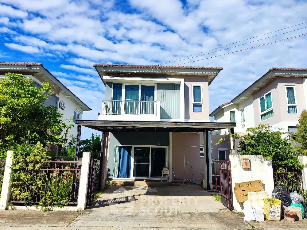 Charming two-story house with driveway and lush greenery under a vibrant blue sky.