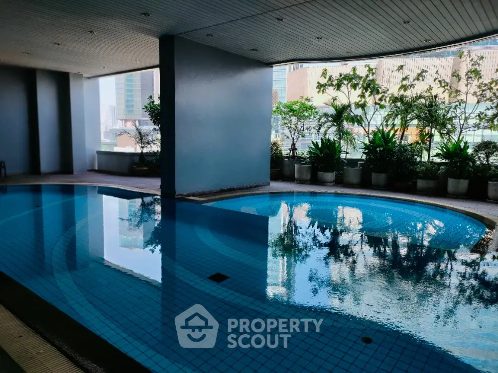 Luxurious indoor pool with city view and lush greenery, perfect for relaxation and leisure.
