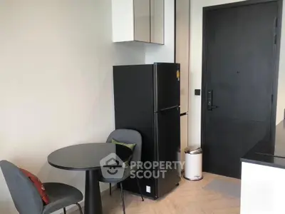 Modern kitchen corner with black fridge and dining set in stylish apartment.