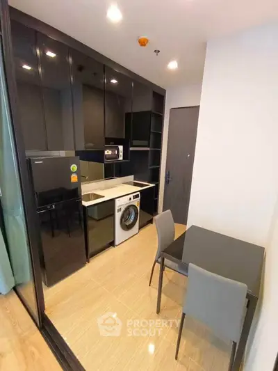 Modern kitchen with sleek black cabinets, integrated appliances, and cozy dining area.