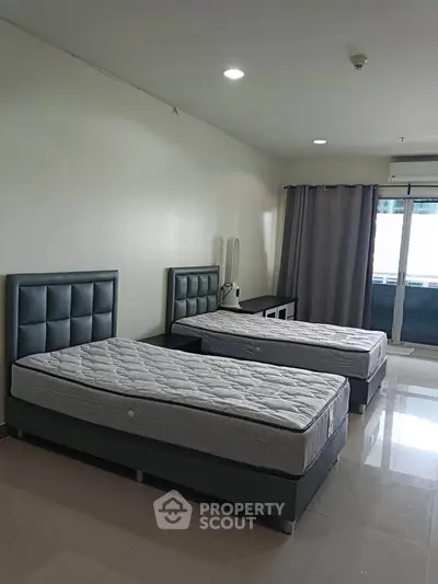 Spacious bedroom with twin beds and modern decor, featuring large windows for natural light.