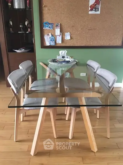 Modern dining area with glass table and stylish chairs on wooden floor.