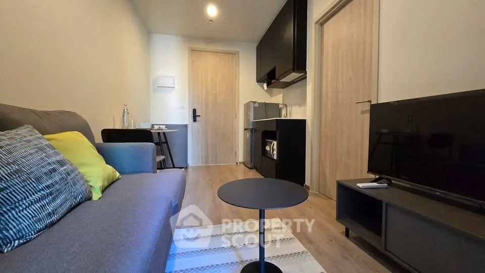 Modern living room with sleek furniture and open kitchen layout in a cozy apartment.