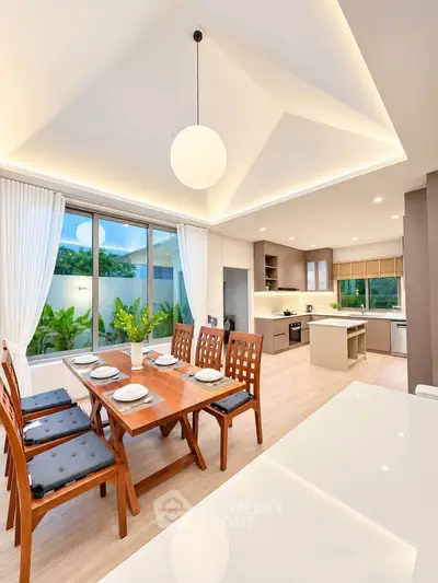 Modern open-layout kitchen and dining area with elegant lighting and garden view.