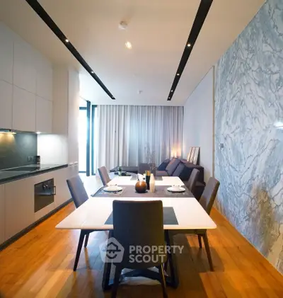 Modern dining area with sleek kitchen and stylish marble accent wall in open-concept apartment.