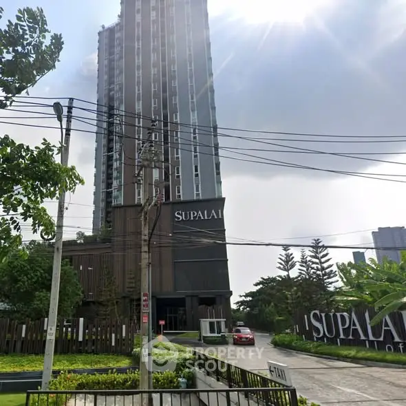 Modern high-rise building with lush greenery and clear sky view.