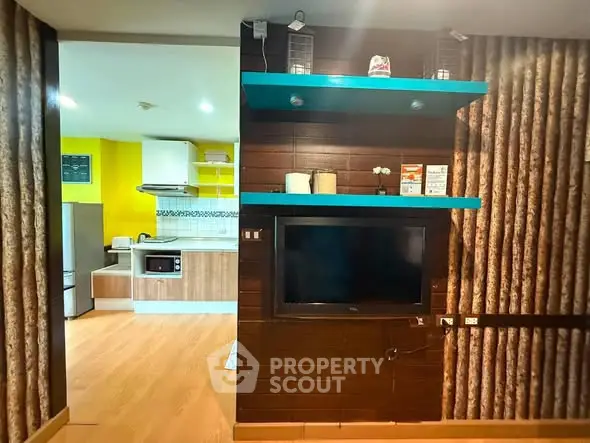 Modern living room with integrated kitchen featuring wood accents and vibrant yellow wall.