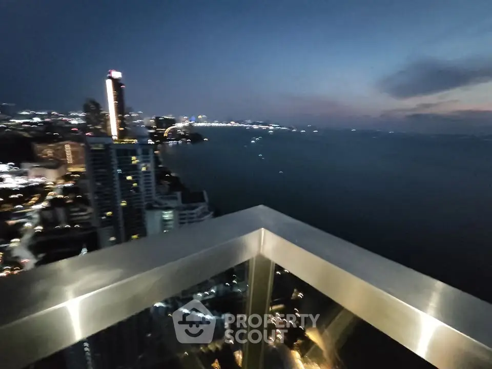 Stunning high-rise balcony view overlooking city skyline and ocean at dusk.