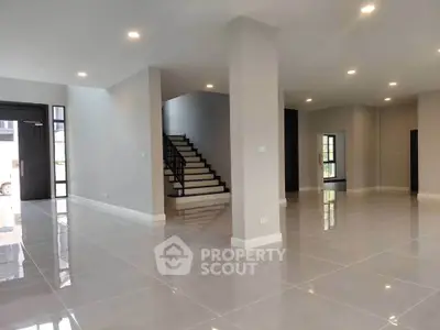 Spacious modern living room with glossy tile flooring and elegant staircase