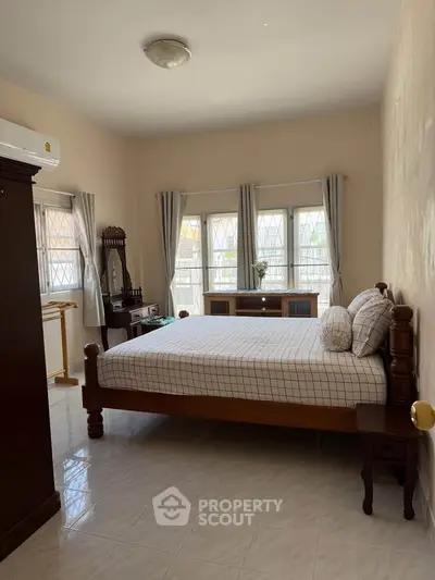 Spacious bedroom with natural light and elegant wooden furniture