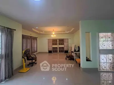 Spacious living room with elegant chandelier and large windows for natural light.