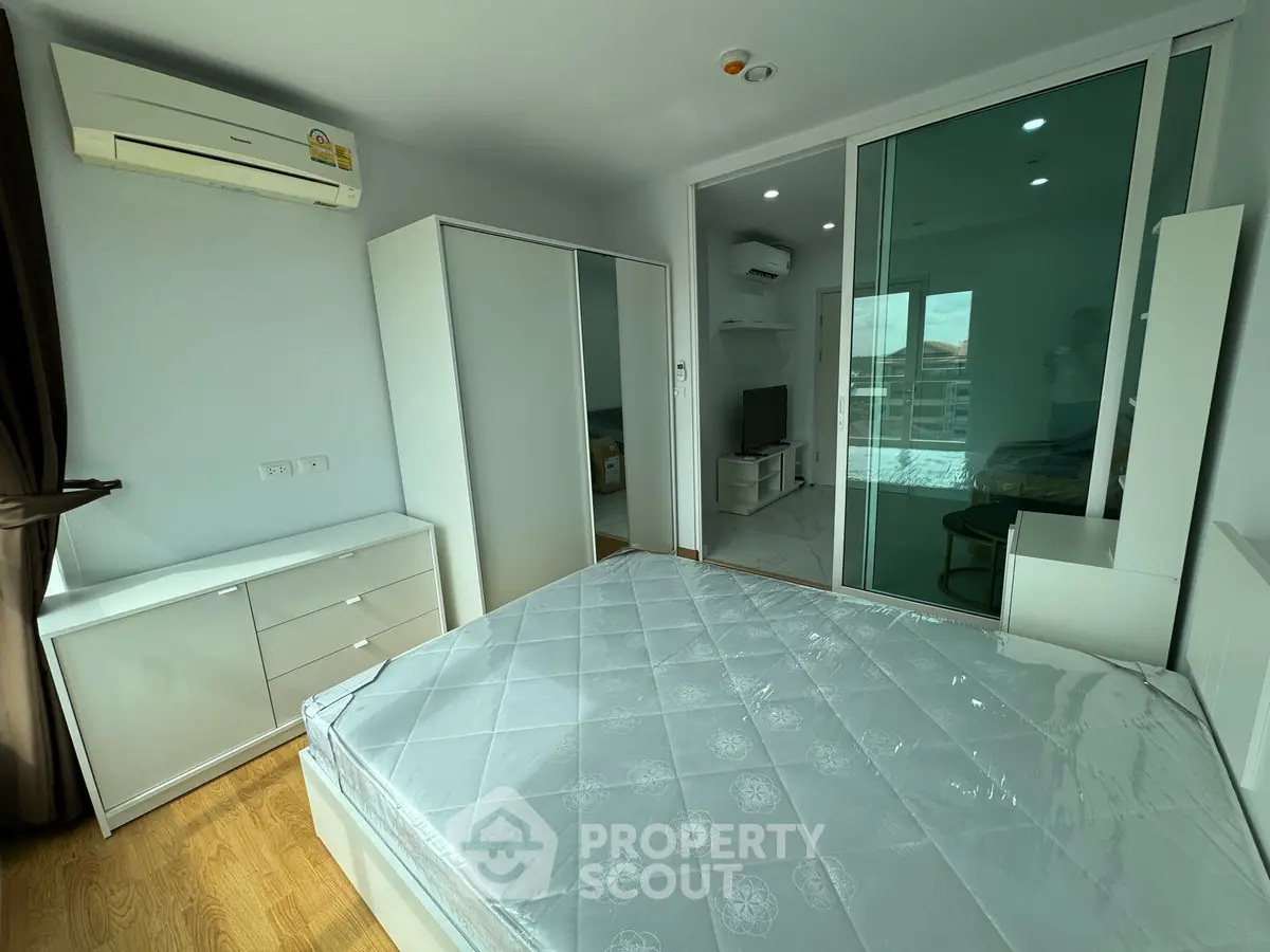 Modern bedroom with sleek white furniture and large mirrored wardrobe.