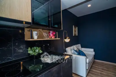 Modern kitchen with sleek black countertops and cozy living area in stylish apartment.